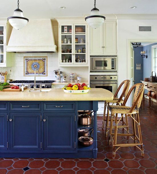 una cucina tradizionale chic con pareti giallo chiaro, armadi e un'isola da cucina blu scuro più piastrelle sul pavimento