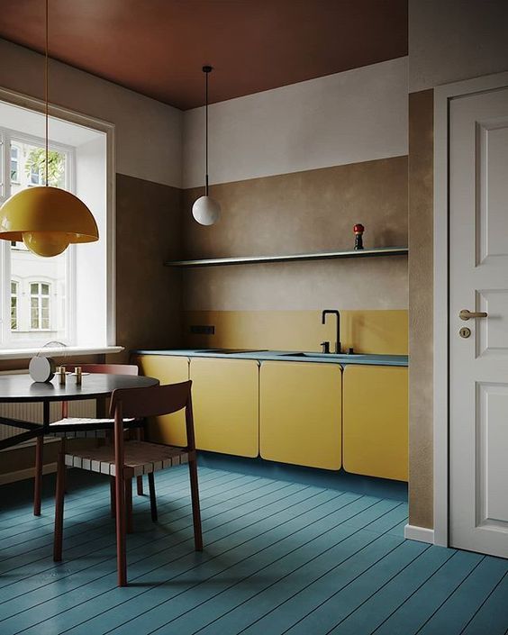 una cucina minimalista blu e gialla con lampade moderne della metà del secolo e armadi in MDF più un soffitto cognac
