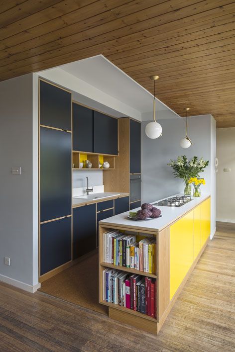 una cucina minimalista in blu marino e giallo brillante, con tocchi di legno naturale e lampade a sospensione