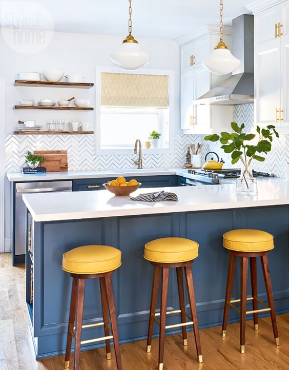 una cucina elegante fatta in blu e bianco, con sgabelli gialli e ripiani bianchi sembra fresca e croccante