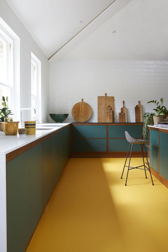 una cucina minimalista fatta con un pavimento giallo sole, armadi turchesi, tocchi di legno colorato e tutte le pareti e il soffitto bianchi