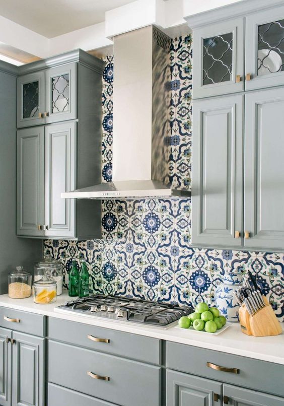 un'elegante cucina grigia con un backsplash di piastrelle a mosaico blu e bianco brillante e controsoffitti bianchi è luminosa e raffinata