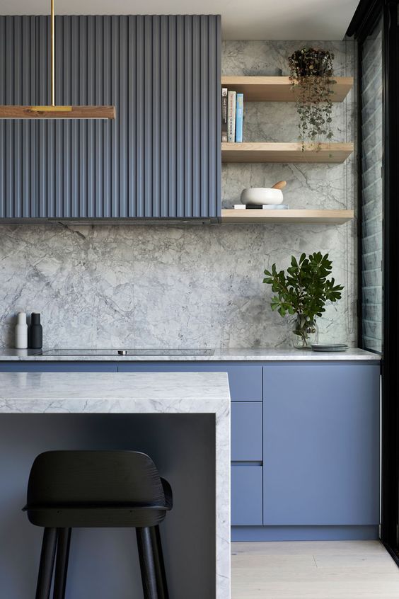 una cucina blu minimalista con alzatina in pietra grigia e controsoffitti più vegetazione in vaso e tocchi d'oro