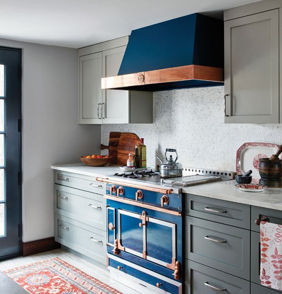 una cucina art déco grigia con un fornello blu brillante e tocchi di rame più un backsplash di piastrelle a mosaico sembra wow