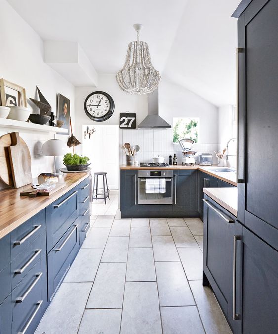 una cucina blu scuro con ripiani in macelleria, un pavimento in piastrelle grigie e un lampadario con perline grigie per un tocco audace
