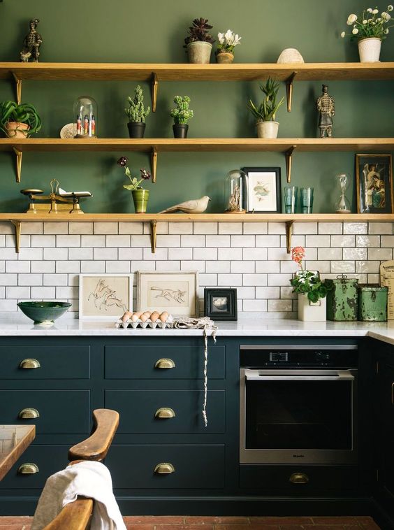 una cucina moderna e accattivante con pareti verdi, piastrelle della metropolitana bianche e armadi verde acqua diluiti con ripiani in legno