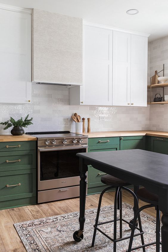 una cucina chic e audace con armadi bianchi e verdi, tocchi metallici, ripiani in legno e un'isola da cucina grigio scuro