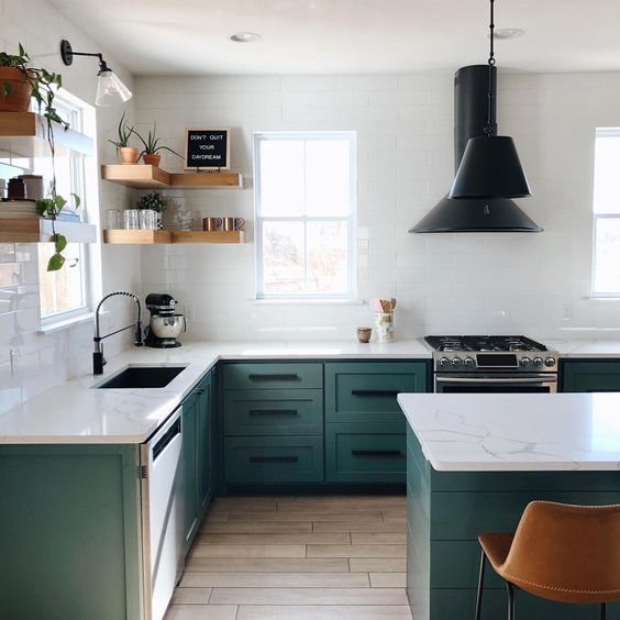 una cucina contemporanea con armadi verdi, pareti in piastrelle bianche, ripiani in pietra bianca e infissi e lampade neri
