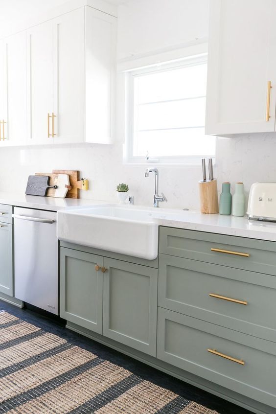 un design da cucina in schiuma di mare verde e bianco con hardware in oro e ottone, con ripiani bianchi e tappeti stampati in tutta la cucina