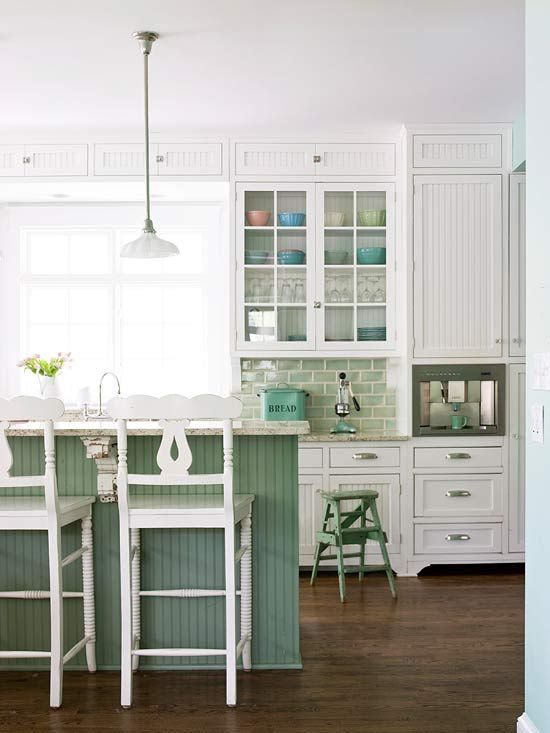 una cucina tradizionale fatta con mobili e mobili bianchi, con un'isola cucina verde e alzatina piastrellata per un tocco di colore