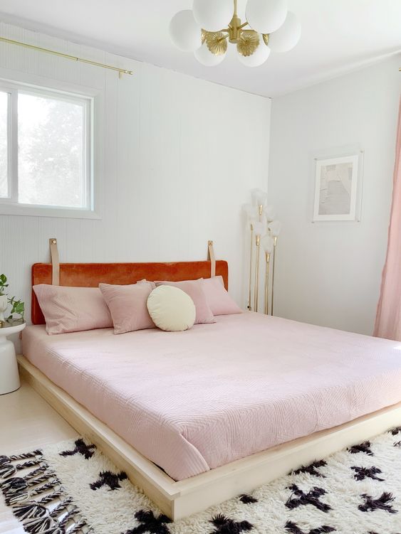 un'accogliente camera da letto da ragazza con biancheria da letto rosa e una testiera in pelle color ambra appesa