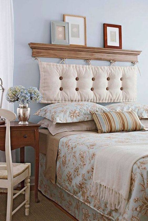 una camera da letto di ispirazione vintage in blu pastello, marrone chiaro e cremoso, con una testiera del cuscino appesa a una piccola mensola