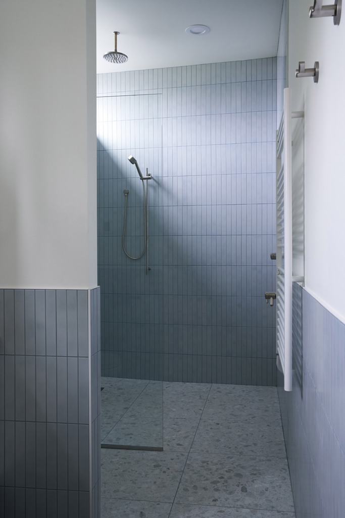 Il bagno è grigio e bianco, con piastrelle lunghe e sottili e un pavimento alla veneziana