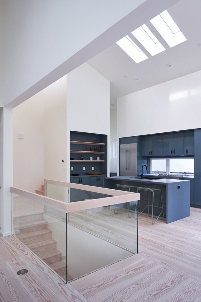 La cucina è minimale, con mobili grigi, con ripiani incorporati e una ringhiera in vetro