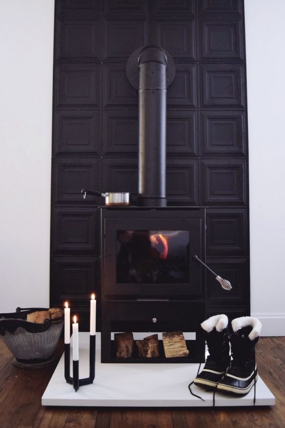 una stufa moderna nera con una parete a pannelli neri dietro e un candelabro moderno per un look audace