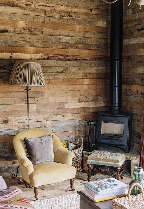 un vintage incontra un angolo di lettura rustico con una stufa a legna, mobili vintage e pareti in legno di recupero