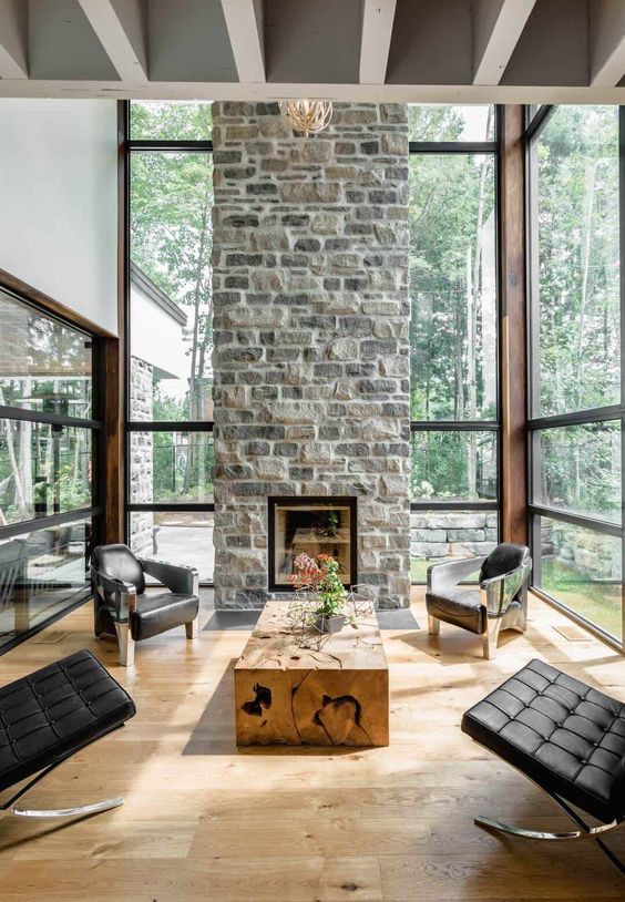 un elegante soggiorno contemporaneo con un camino in pietra come centrotavola, sedie in pelle nera e un tavolo in lastre di legno