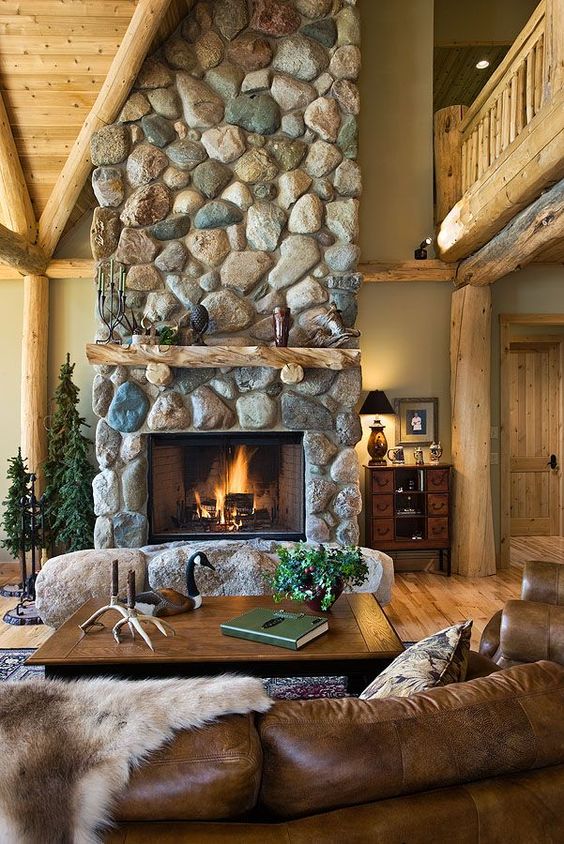 uno splendido spazio cabina con un grande camino in pietra con pietre alla base, mobili in pelle e legno