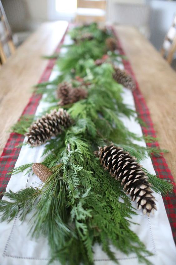 una ghirlanda di vegetazione lussureggiante con pigne è una bella decorazione da tavola per Natale