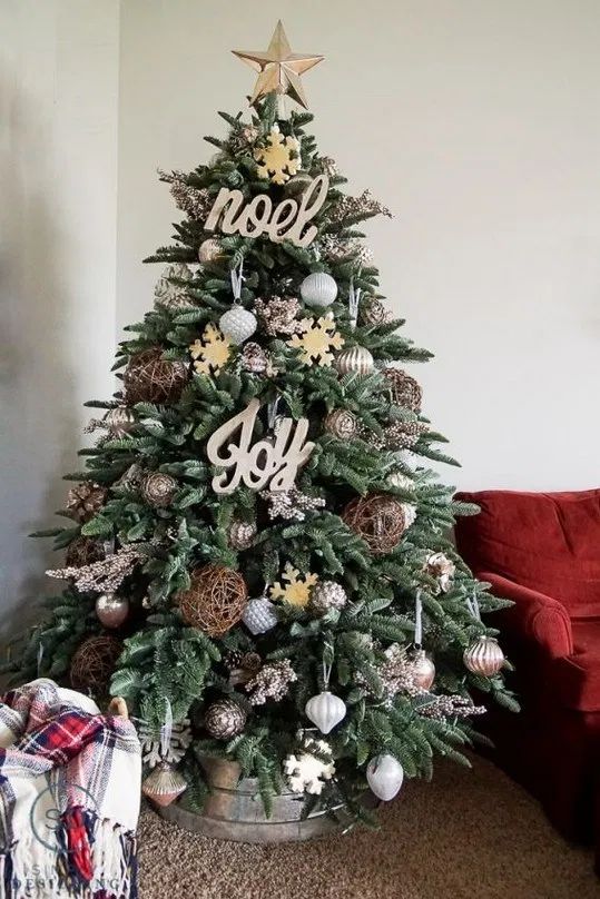 un albero di Natale di una fattoria con ornamenti metallici e di grandi dimensioni, cartelli in legno e fiocchi di neve più una base di secchio zincata