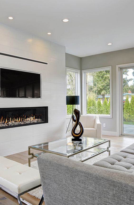 un caminetto minimalista bianco incorporato sotto la TV è un'idea elegante ed elegante che aggiunge intimità