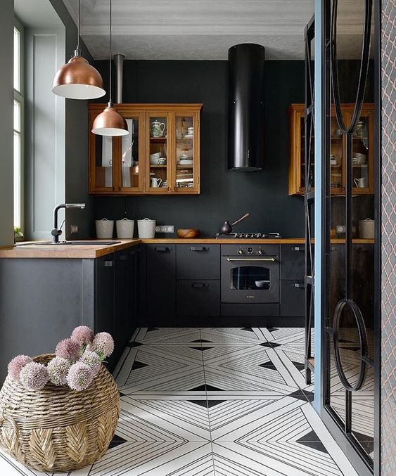 un'accogliente cucina eclettica fatta con armadi e piani di lavoro dai colori intensi, con lampade a sospensione in rame