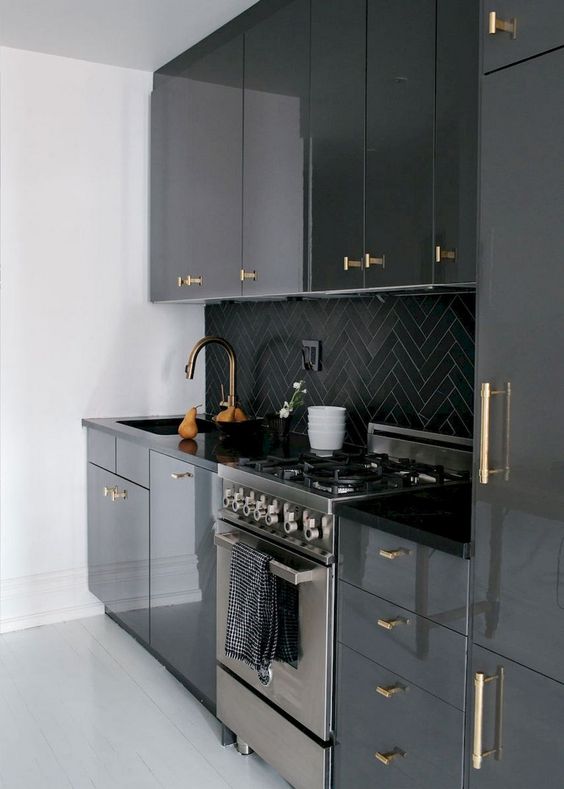 una moderna cucina nera rinfrescata con superfici bianche e con maniglie dorate dappertutto che aggiungono un tocco di glamour
