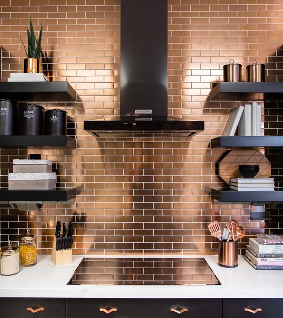 una moderna cucina nera con un piano di lavoro bianco e un alzatina in piastrelle di rame per un accento luminoso e brillante