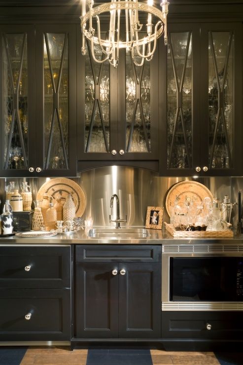 una cucina nera di ispirazione vintage con alzatina metallica, piani di lavoro ed elettrodomestici sembra molto audace