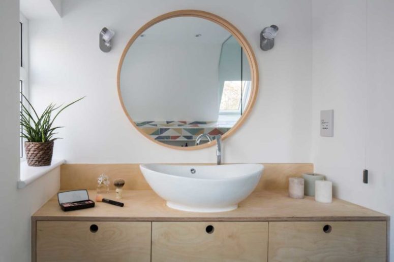 Il bagno è realizzato con un lavabo in compensato, un lavandino ovale e uno specchio rotondo