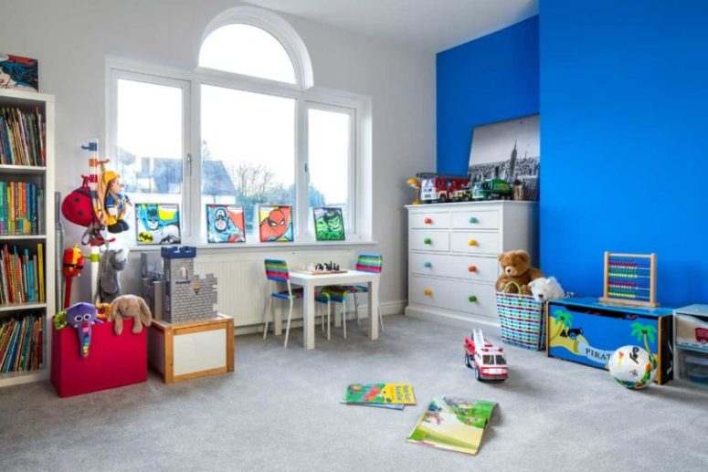 La stanza dei bambini è luminosa e divertente, con un muro blu, con poster colorati e tanti giocattoli