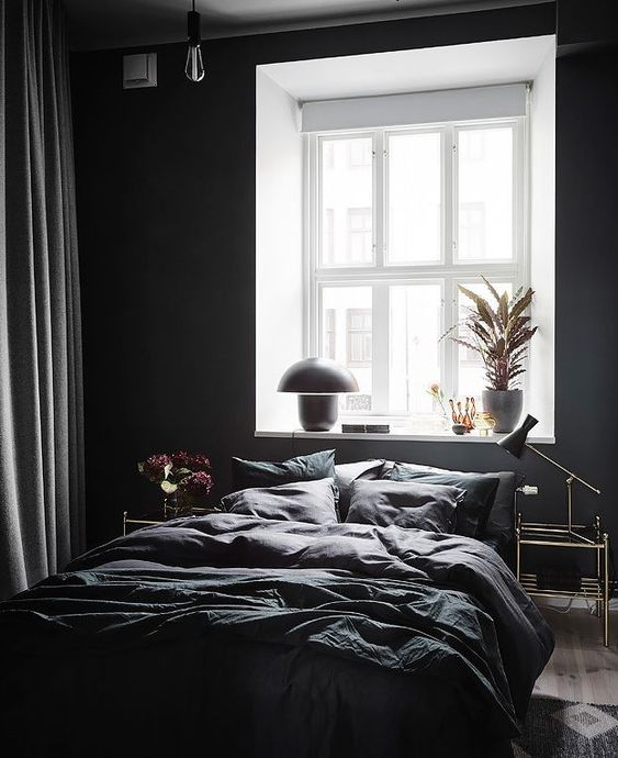 una camera da letto contemporanea con pareti nere, alcune lampadine e lampade e un set di biancheria da letto scura