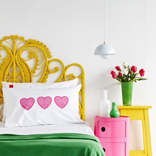 una testiera gialla intrecciata creativa si abbina alla combinazione di colori vivaci della camera da letto