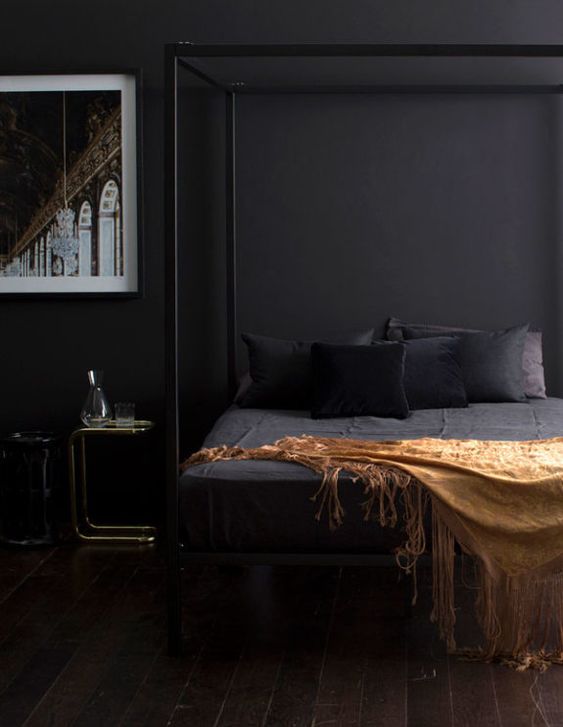 una camera da letto elegante e lunatica con pareti nere, un letto incorniciato e un'opera d'arte appariscente sembra molto rilassante