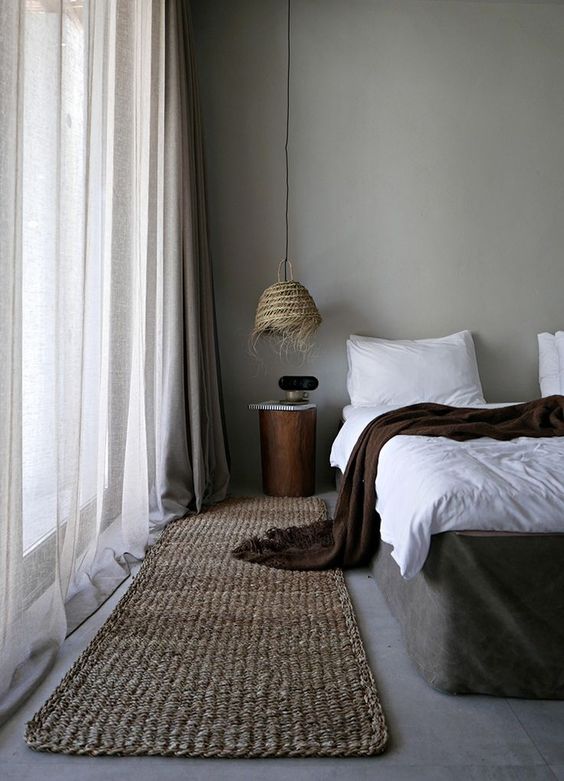 una camera da letto con molta consistenza: iuta, vimini, vari tessuti e pareti e pavimenti di cemento