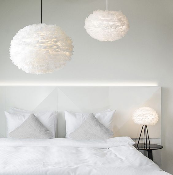 grandi e soffici lampade a sospensione in piume e una da tavolo che riecheggia creano un'atmosfera ariosa nella camera da letto