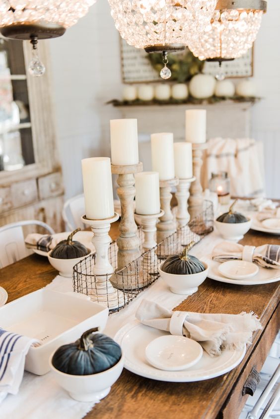 un tavolo da pranzo chic neutro con zucche in tessuto scuro, candelabri in legno e tovaglioli a righe