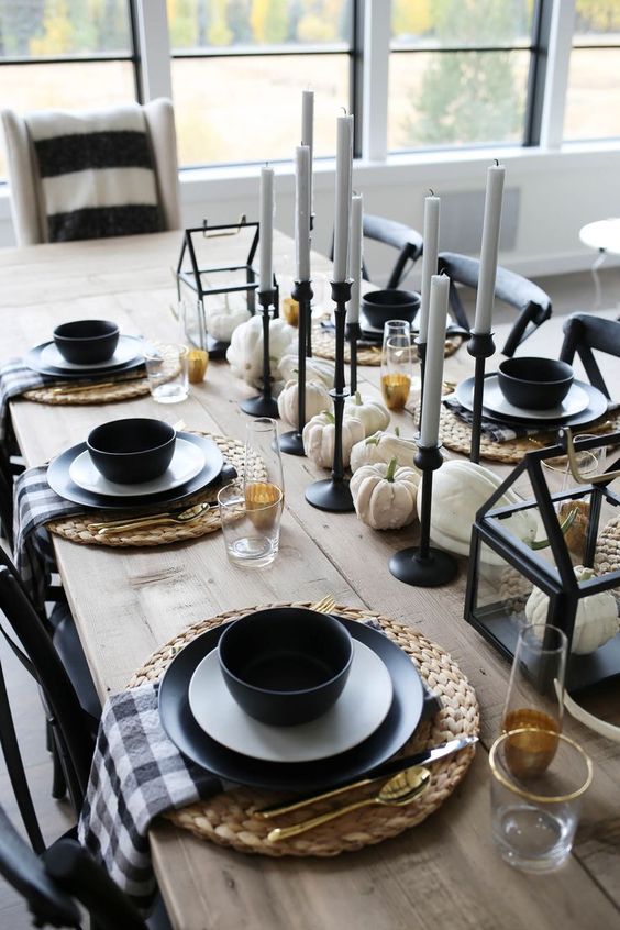 un elegante panorama da tavola moderno con tovaglioli scozzesi, stoviglie e candelabri blakc, zucche bianche e candele