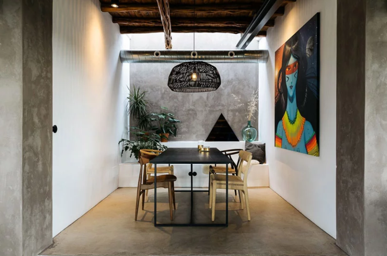 C'è uno spazio da pranzo al coperto, con una grande opera d'arte, un moderno tavolo nero e sedie in rattan