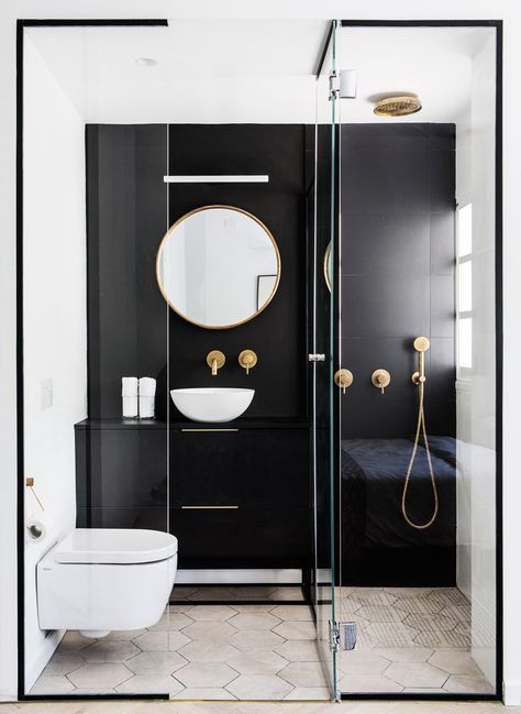 un piccolo bagno a contrasto con una parete nera e un trucco, una doccia, uno specchio rotondo e una ciotola