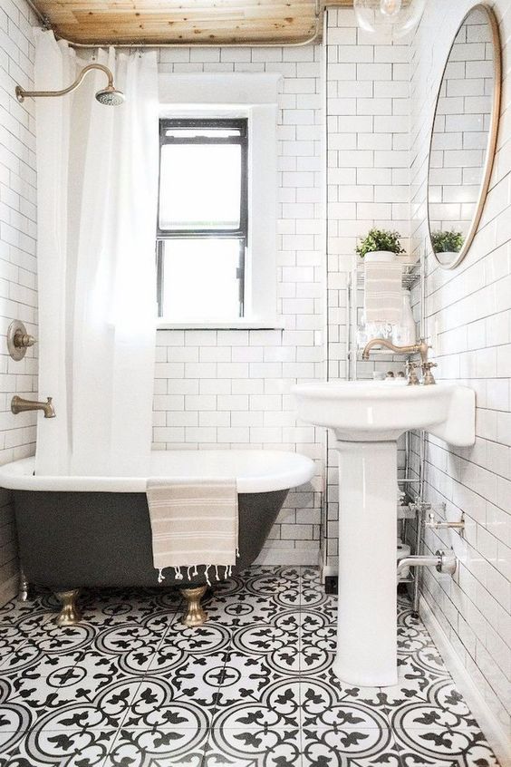 un bagno piccolo e luminoso con pavimento a mosaico, soffitto in legno, vasca con piedini neri e lavabo da appoggio