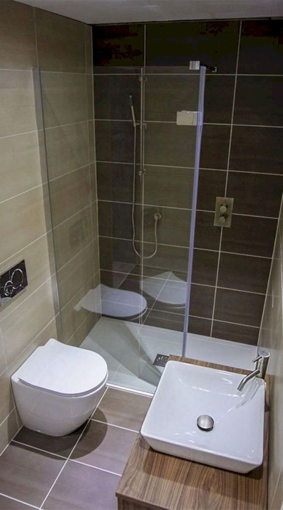 un bagno minimalista fatto con piastrelle terrose e sabbiose, un lavabo in legno con un lavandino quadrato e uno spazio doccia
