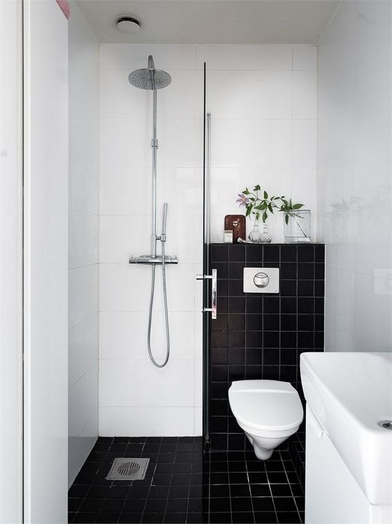 un piccolo bagno in contrasto con piastrelle bianche e nere, uno spazio doccia, un lavandino e del verde per rinfrescare l'aspetto
