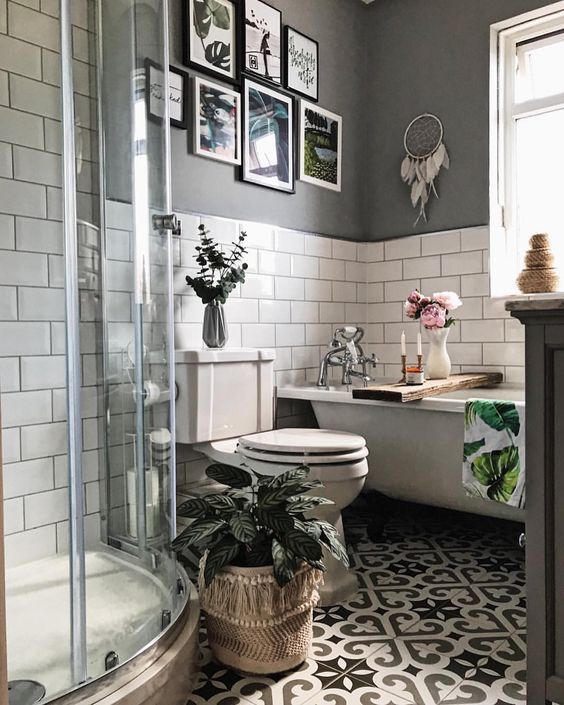 un piccolo bagno boho con pareti piastrellate della metropolitana grigie e bianche, uno spazio doccia, un muro della galleria e vegetazione in vaso