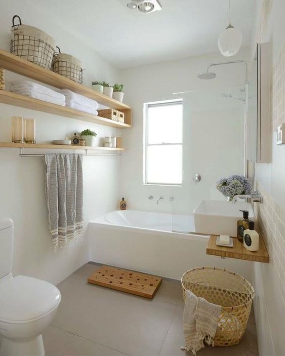 un piccolo e sereno bagno con vasca, scaffali aperti, un lavandino, vimini e tocchi di legno qua e là