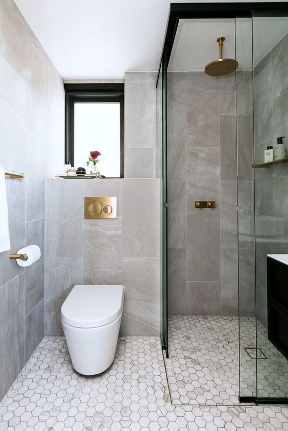 un elegante bagno contemporaneo con piastrelle in pietra e marmo, una finestra, uno spazio doccia e tocchi dorati