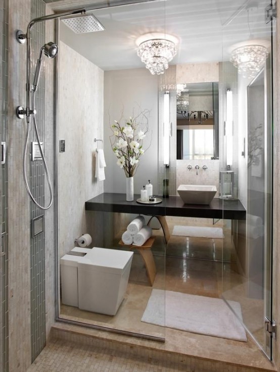 un raffinato piccolo bagno con piastrelle in pietra, un lampadario di cristallo, uno spazio doccia e una vanità scura incorporata