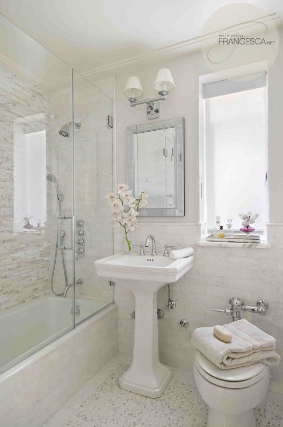 un bagno neutro realizzato con tre tipologie di piastrelle, una vasca con vano doccia in uno, un lavabo free-standing ed eleganti lampade
