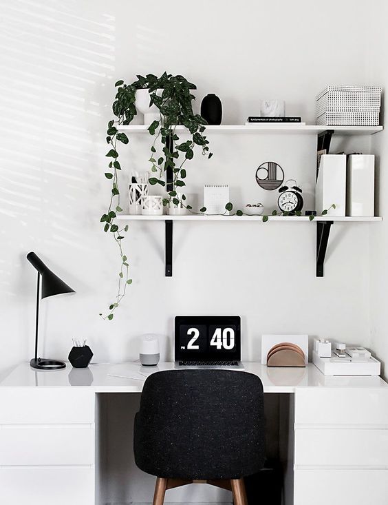 un angolo scandinavo dell'home office con una scrivania bianca, una sedia nera, una lampada e alcuni scaffali a parete