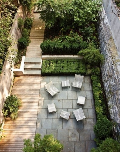un giardino in una residenza di città contemporanea con un ponte in legno e piastrelle di cemento, mobili contemporanei e vegetazione piantumata